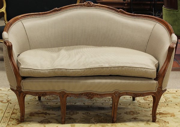 Rococo style settee: Rococo style walnut settee, having a carved floral medallion centering the continuous crest terminating at the inswept returns and rising on cabriole legs, 36''h x 59''w