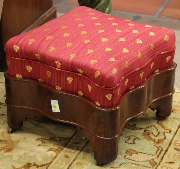 William IV footstool: William IV mahogany footstool, having a shaped upholstered top above a conforming base rising on bracket feet ending on casters, 14''h