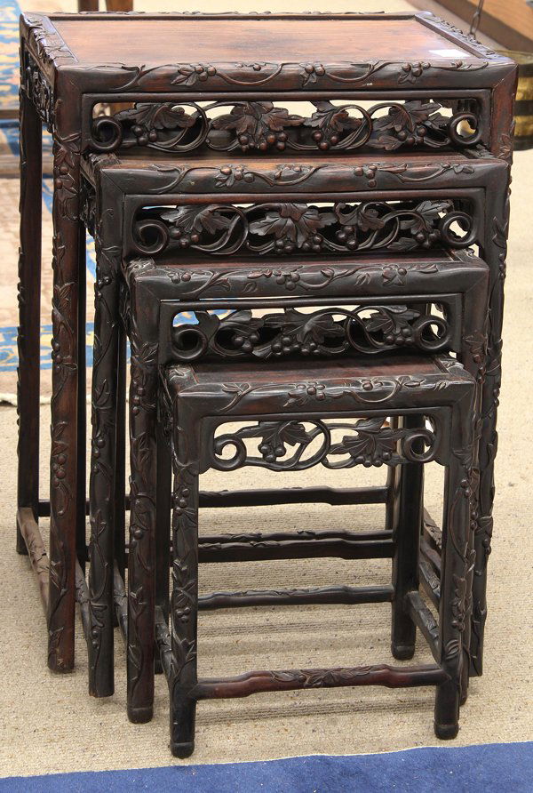 Chinese Carved Nesting Tables: Set of Chinese wooden nesting tables, each inset with a floating top framed within an edge carved with scrolling tendrils suspending an abundance of fruits, similar pattern repeated onto the reticulat
