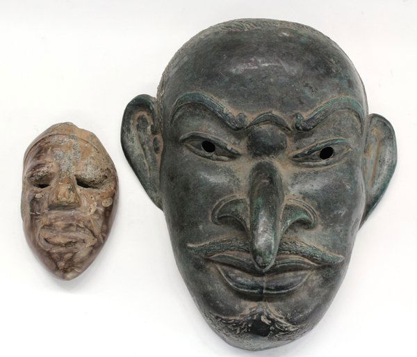 Masks: (lot of 2) Masks, cultures uncertain, the larger is of bronze, green and has a long down-pointing nose and a mustache; the smaller is of stone, larger: 8.5''h x 7''w. Provenance: The Hemphill Collecti