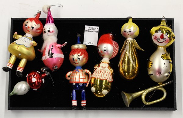 Christmas ornaments: (lot of 15) Group of Christmas tree ornaments including Raggedy Ann and Andy, elf on the moon, bugle, together with a ceramic bell painted red with a Christmas desert scene