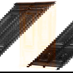 A Gothic Revival walnut cabinet: A Gothic Revival walnut cabinet, Northern France, circa 1880, the high relief carved case with paneled doors, the lower panels with carved figural medallions, and rising on block feet, 80"h x 47"w x 2