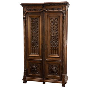 A Gothic Revival walnut cabinet: A Gothic Revival walnut cabinet, Northern France, circa 1880, the high relief carved case with paneled doors, the lower panels with carved figural medallions, and rising on block feet, 80"h x 47"w x