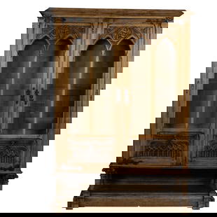 A Gothic Revival walnut cabinet, Northern France, circa 1880: A Gothic Revival walnut cabinet, Northern France, circa 1880, the high relief carved case with glazed doors, the lower panels with carved linen fold and floral medallions, and rising on platform base,