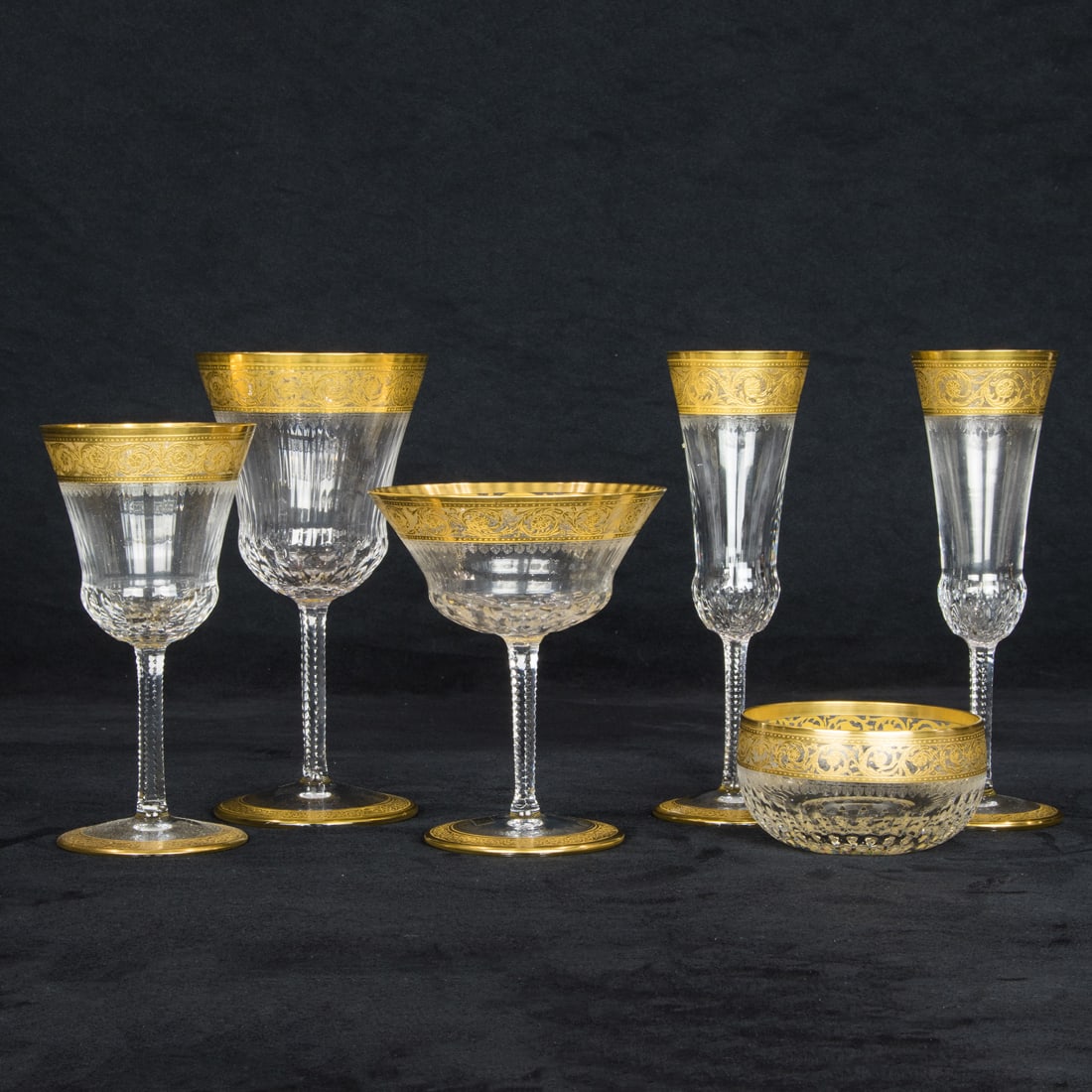 A St. Louis gilt rimmed and cut glass suite of stemware in the Thistle pattern: A St. Louis gilt rimmed and cut glass suite of stemware in the Thistle pattern, 20th century, each with acid etched factory mark, comprising (12) water goblets, 7.5"h; (7) Continental goblets, 7"h; (1