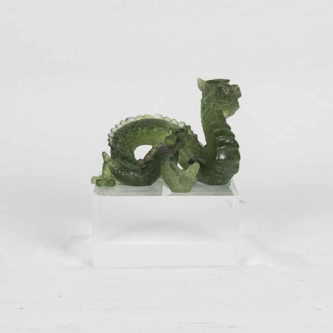 A Daum limited edition pate de verre glass dragon on acrylic stand: A Daum limited edition pate de verre glass dragon on acrylic stand, engraved indistinctly 'Daum France 884/2000', 3"h x 4.5"l. Provenance: Property from the estate of internationally recognized textil