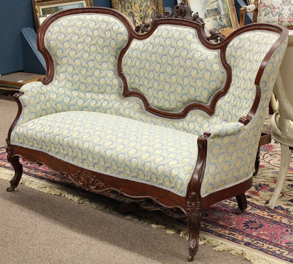 Rococo Revival settee: Rococo Revival settee, Grand Rapids circa 1860, executed in mahogany, the carved crest above the segmented back continuing to the outswept arms, and rising on cabriole legs centered with a shaped flam