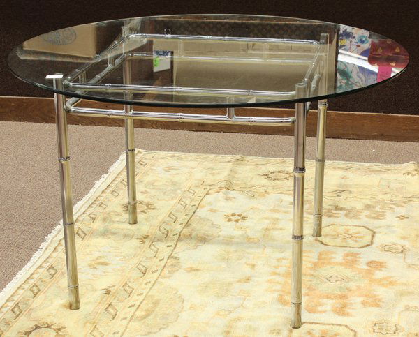 Arthur Court style dining table: Arthur Court style dining table, the circular plate glass top above the polished aluminum base having a conjoined double apron and rising on faux bamboo legs, 29''h x 48''w, Proceeds to benefit The Sa