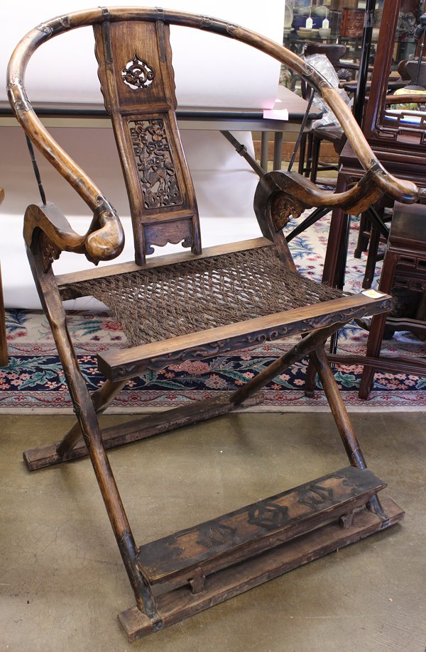 Chinese Wooden Folding Chair: Chinese horseshoe back folding chair, the back reticulated with a qilin below a floating gourd, the rope seat fronted by an apron carved with a pair of stylized dragons, crossed supports connected by 
