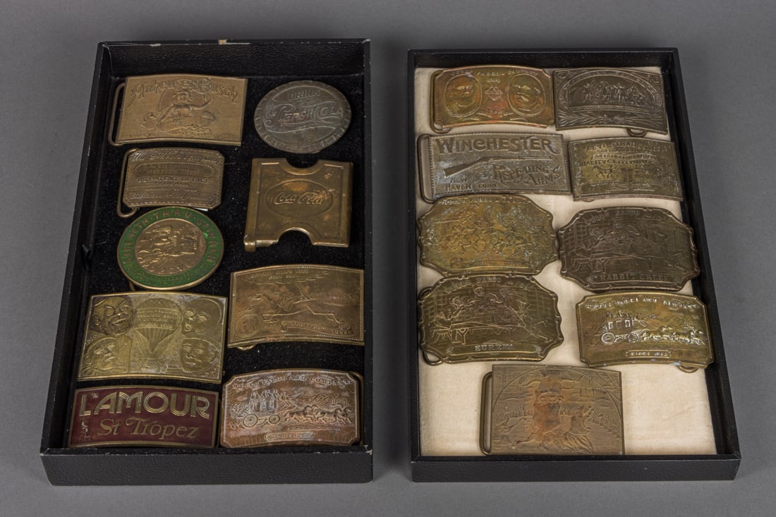 A collection of eighteen brass buckles: A collection of eighteen brass buckles, most by Tiffany & Co and having an Advertising or a Historical theme, including an 'Anheuser Busch"; both a Coke and a Pepsi Cola; an English 'Levi Strauss & Co