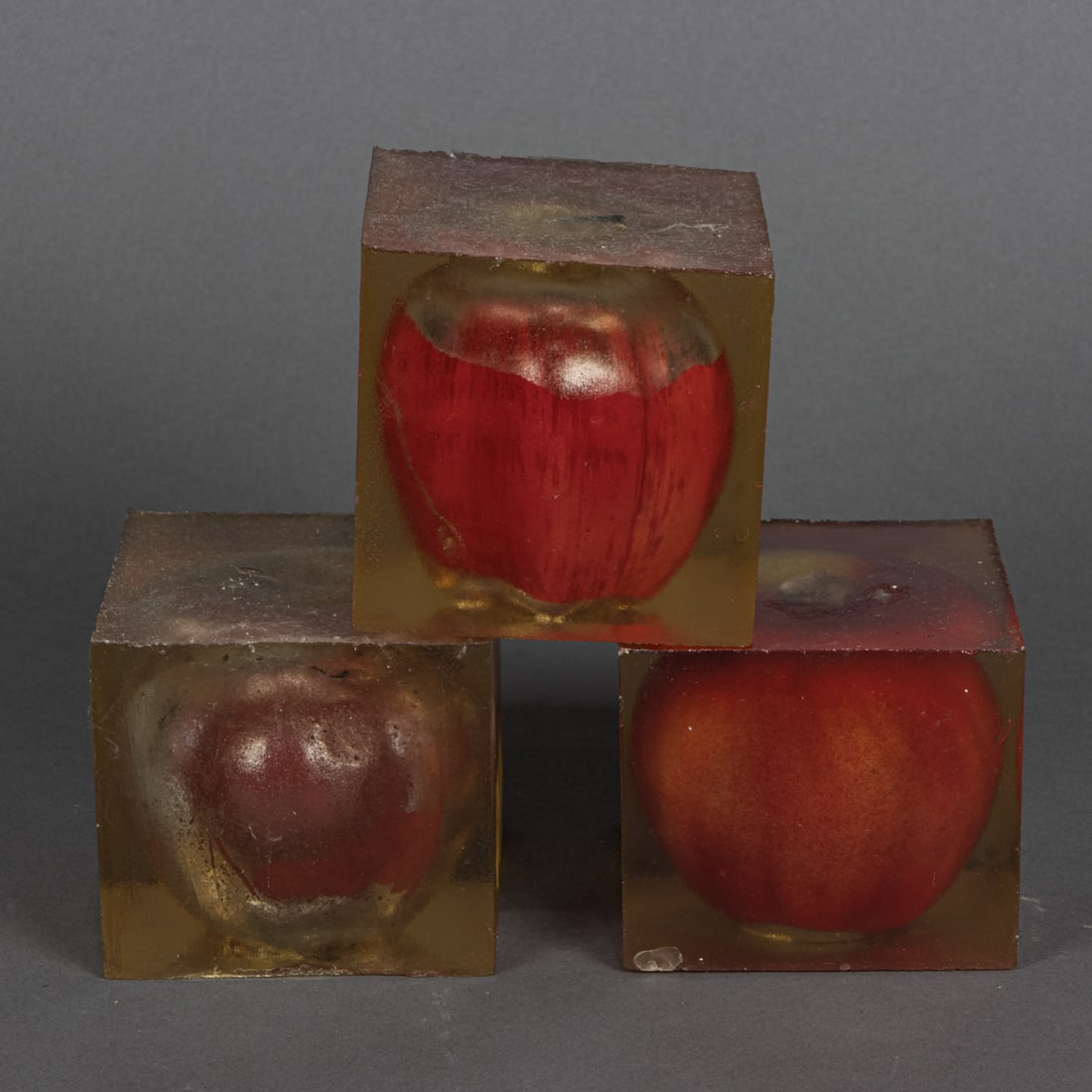 A set of three Lucy Puls resin blocks: Trim Malum: A set of three Lucy Puls resin blocks: Trim Malum, 1991, each enclosing a plastic apple., 2.75"h. Provenance: with receipt for Stephen Wirtz Gallery, San Francisco