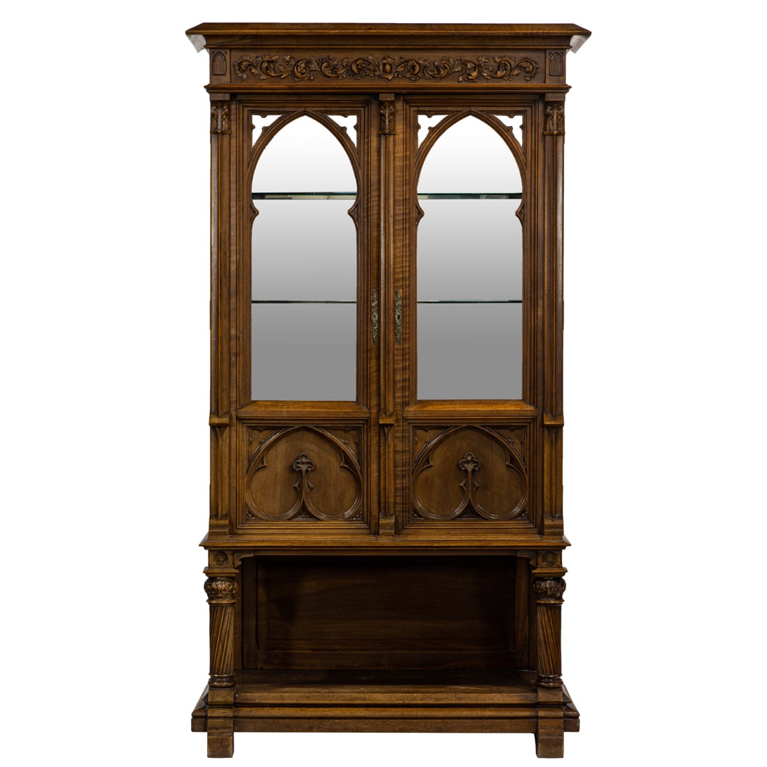 A French Gothic Revival vitrine: A French Gothic Revival vitrine, circa 1890, the relief decorated case with two doors opening to the fixed shelves resting on the carved columnar supports terminating on the lower tier and rising on b