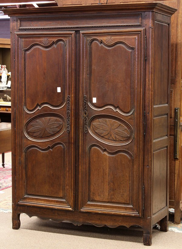 French Provincial armoire: French possibly Brittany Provincial linen press, late 18th century, the two door panelled case having oval reserves centered with carved leaf accents forming a starflower, and retains original hardwar