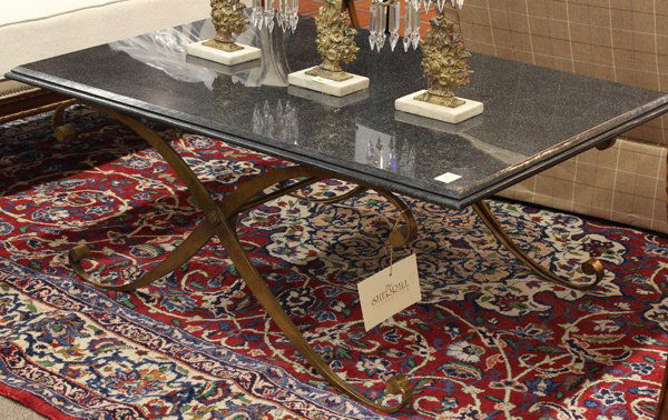 John Richard cocktail table: John Richard cocktail table, the rectangular noir marble top having a graduated edge above a gilt metal X form base terminating on upswept feet, 21''h x 49''w x 33''d Provenance: From the Design Cente