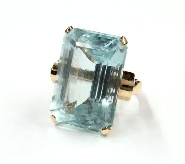 14K yellow gold Retro era aquamarine ring: Lady's Retro era ring with scroll accents; mounted in 14K yellow gold and featuring (1) cut-corner rectangular step cut aquamarine, approximately 56.88 ct. Ring weighs 22.5 grams and is size 6.