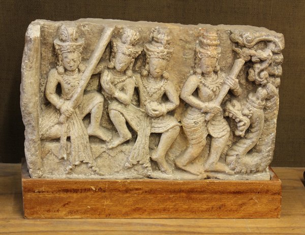 Southeast Asian Carved Stone Figural Group: Southeast Asian stone frieze, featuring four elaborately adorned dancers standing in front of a meandering naga, with wooden stand, stone: 18''w