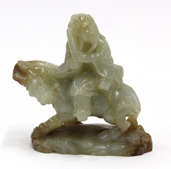 Chinese Jade Carving of Zhang Guo Lao: Chinese jade figural carving, featuring Zhang Guo Lao of the Eight Daoist Immortals, holding a fishing drum and seated on his donkey supported on a plinth, the celadon matrix with russet inclusions, 3