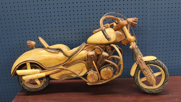 Wood carved sculpture: Art carved motorcycle sculpture, depicting a V Twin Harley Davidson and executed in multiple woods, the wheels made of twined grape vines, 19.5''h x 36''l Provenance: The Hemphill Collection of San Fr