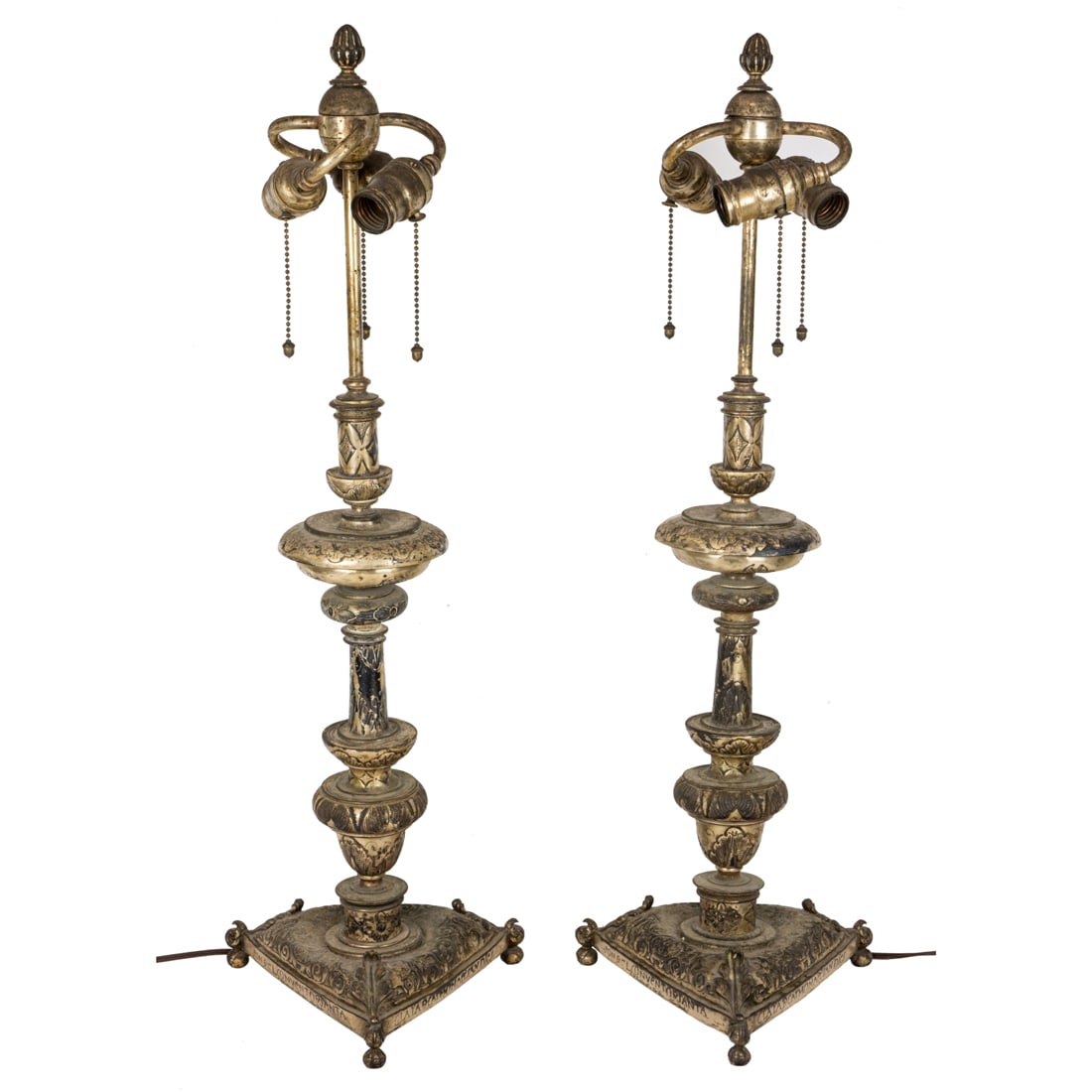 Pair of Spanish baroque brass tripod pricket sticks: A pair of J.F. Caldwell & Co silvered brass repousse candlestick lamps, early 20th century, each in the Spanish Baroque taste with knopped urn standard raised on triangular base with Latin inscription
