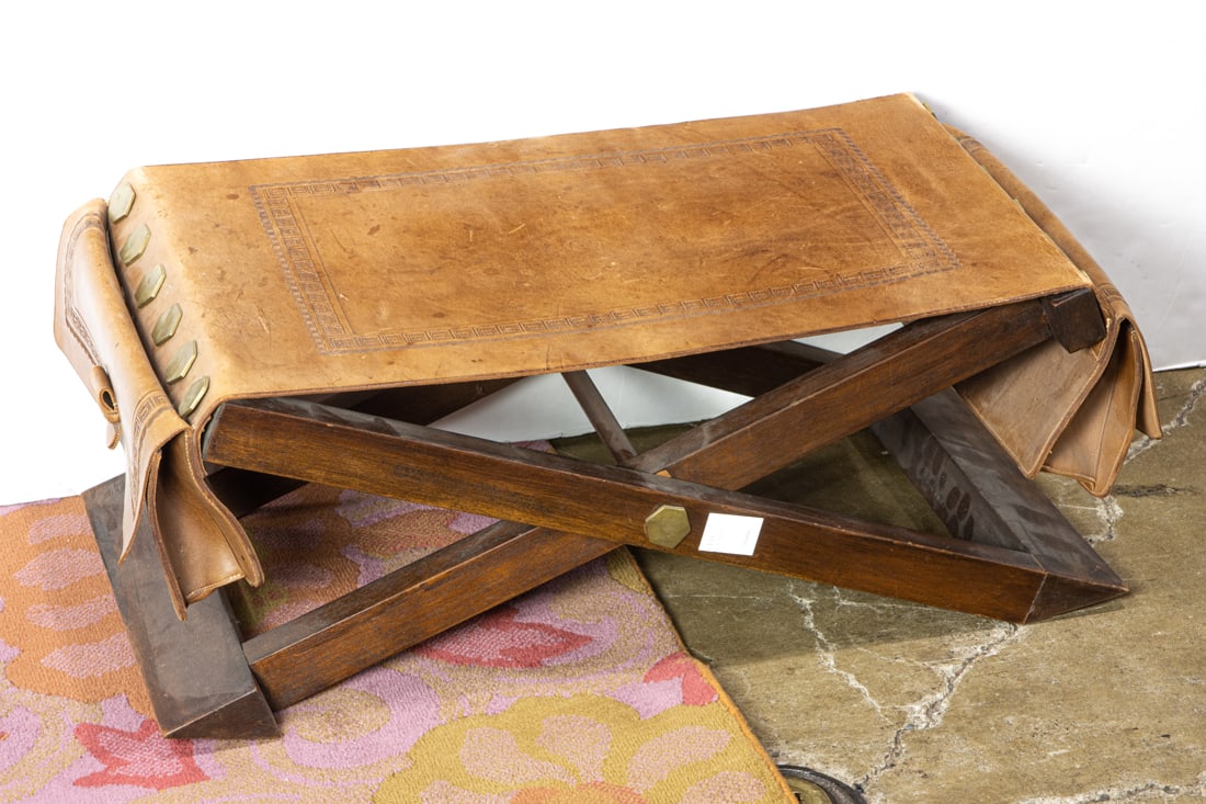 A Persian low tooled leather bench on x-form base: A low tooled leather bench on x-form base, 30?w. Provenance: Estate of Meri Jaye (San Francisco, California). Ms. Jaye was a renowned, San Francisco interior designer of passenger and cargo ships, as 