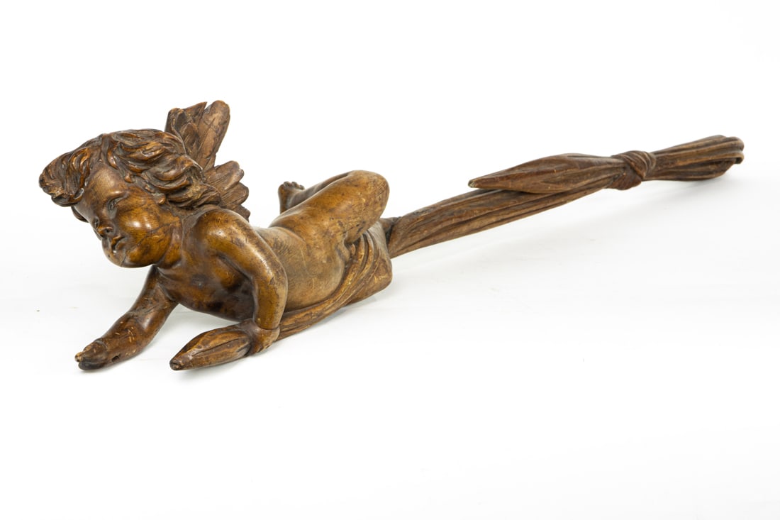A Baroque style carved wood figure of a putto, 19th century: A Baroque style carved wood figure of a putto, 19th century, depicted suspended from a tied drape, 41"l. Provenance: Estate of Meri Jaye (San Francisco, California).
