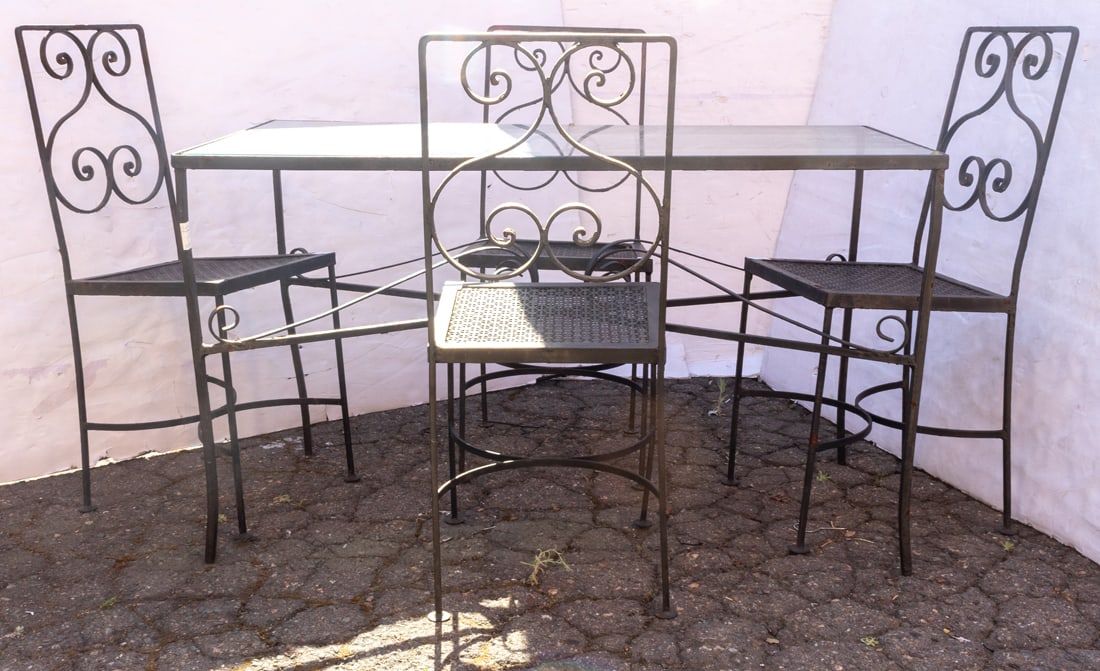 An outdoor iron and glass dining table and four chairs: An outdoor iron and glass dining table and four chairs, table 28"h x 28"w x 26"d; chairs 36"h x 15"w, 18.5"h of seat.