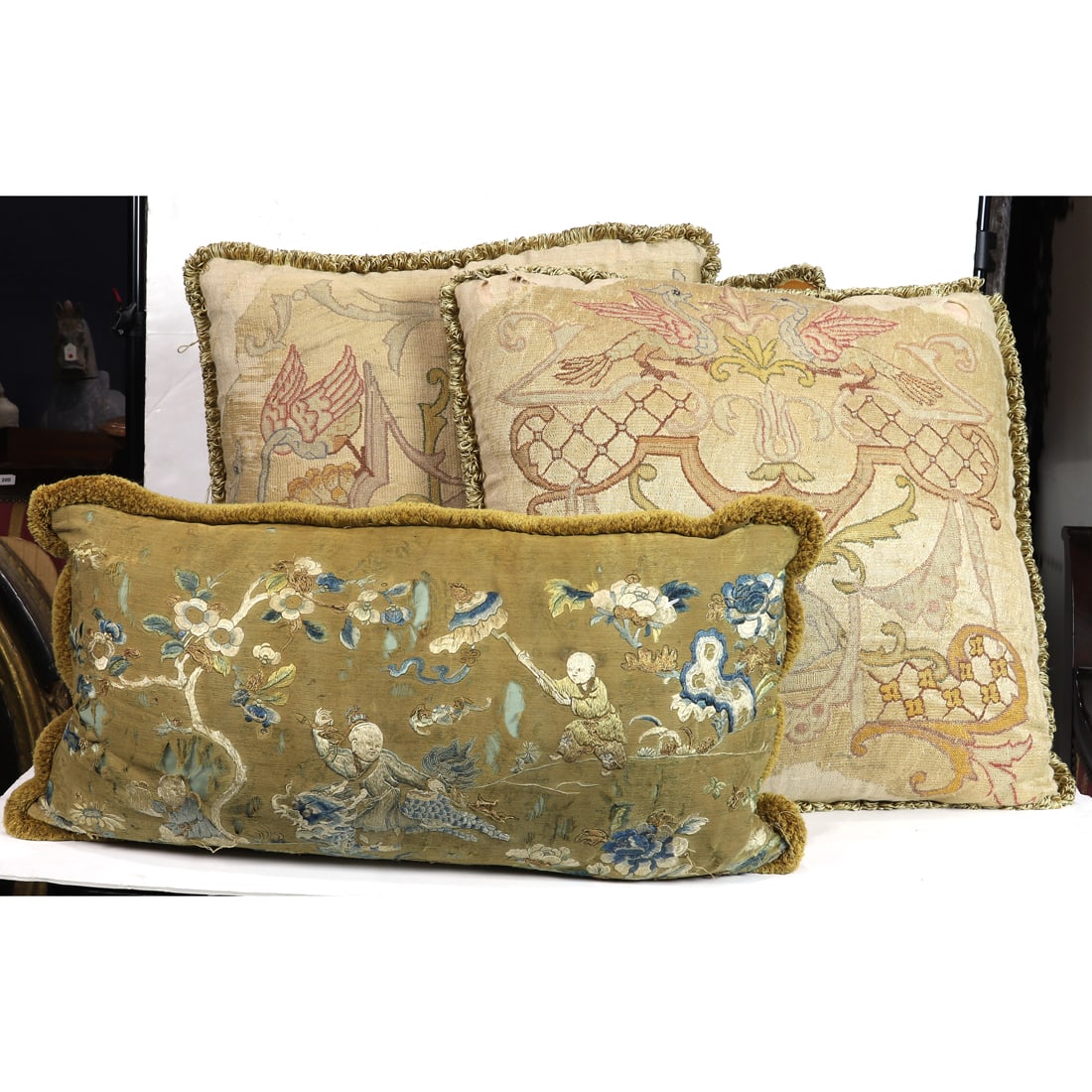 Four antique textile fragment pillows: Four antique textile fragment pillows, comprising a pair and single Continental pillows, each with velvet backing and silk fringe, approximately 22" x 22" and a single Chinese embroidered silk pillow,