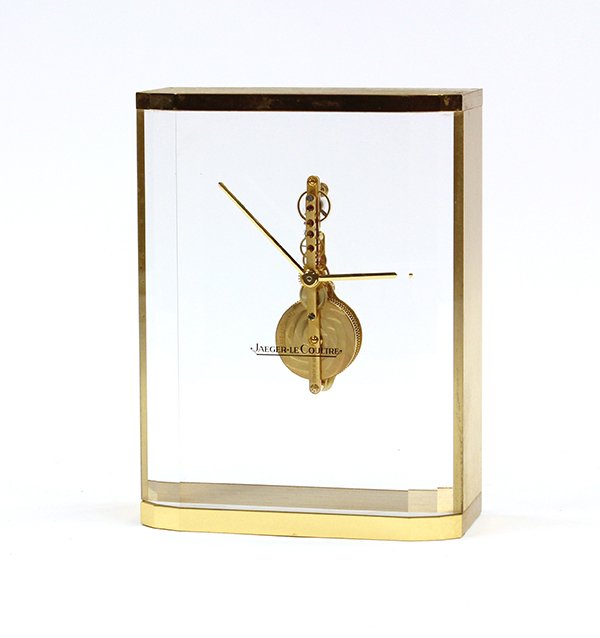 Jaeger Le Coultre clock: Jaeger Le Coultre shelf clock, executed in the Art Deco taste, the brass case centering the double window housing the skeleton movement marked Swiss 16 jewels, and rising on a conforming base numbered