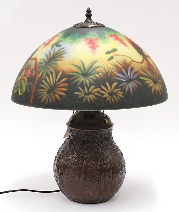 Reverse painted table lamp: Reverse painted table lamp executed in the 'Jungle Bird' pattern, depicting wild parrots in a naturalistic setting above the three light cluster rising on a patinated metal bulbous base, 23''h x 17''w