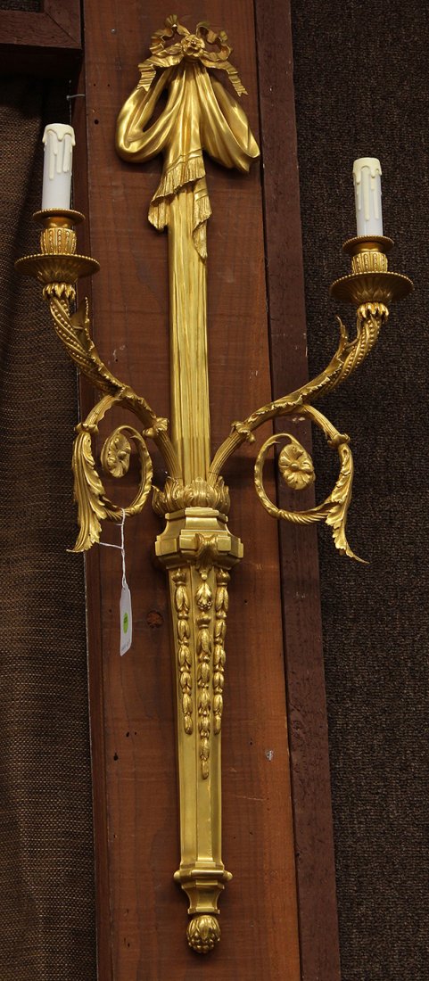 Gilt bronze wall sconces: Louis XVI style gilt bronze wall sconces, the two light fixtures having a bow form medallion surmounting the fluted standard supporting the two arms having acanthus and rosette detail above the plinth