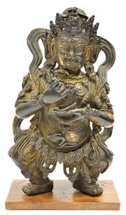 Himalayan Bronze Mahakala, 18th/19th c: Himalayan gilt bronze figure of Mahakala, 18th/19th century, the dharmapala adorned with a necklace of heads and clutching a karttrka and kapala (ritual chopper and skull cup), the stern face surmount