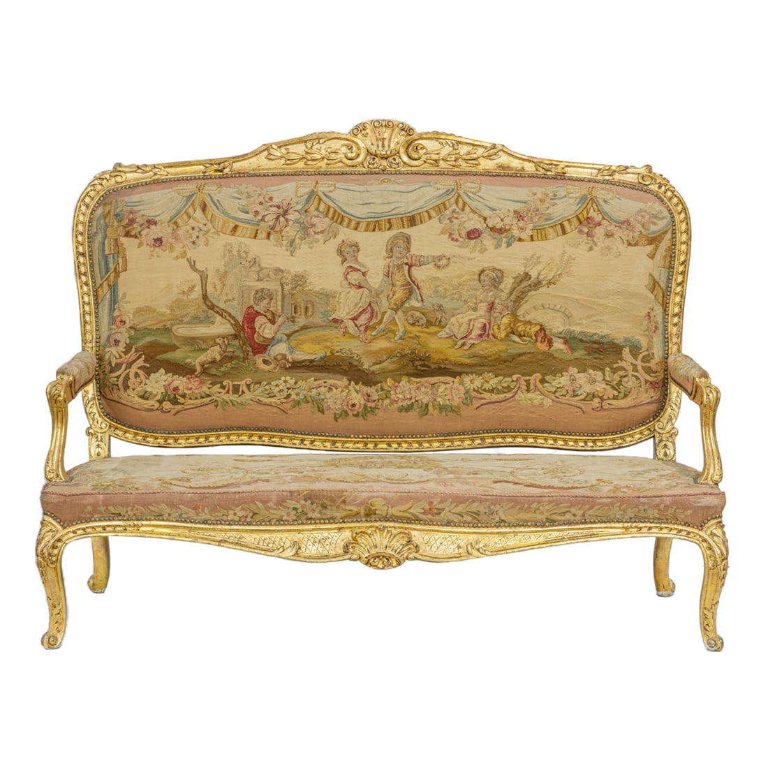 A French Louis XV style giltwood settee circa 1900: A French Louis XV style giltwood settee circa 1900, the large form with a carved shell and garland crest surmounting the original petit point show cover depicting a genre scene with figures in a natur