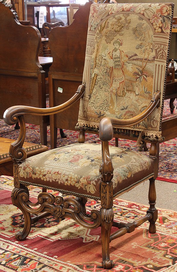 Continental carved fireside chair: Continental carved fireside chair, 19th century, the rectangular back covered in needlepoint depicting a courting scene, the couple embraced in a country setting, with outswept arms above the carved r