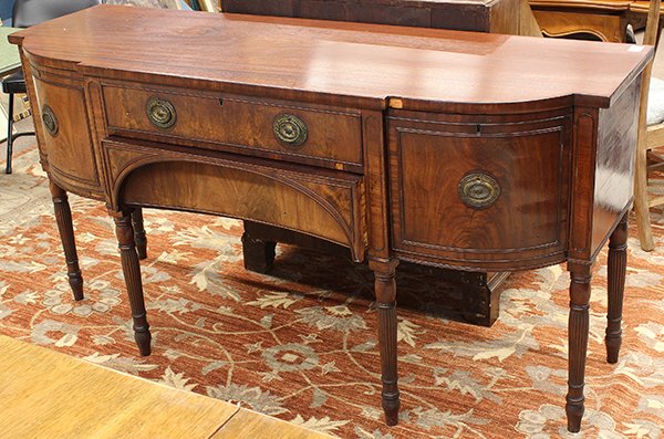 Hepplewhite mahogany sideboard: Hepplewhite mahogany sideboard, the shaped top above a conforming case centered with two drawers and rising on reeded legs terminating on tapered feet, 36.5"h x 72"l w x 24"d
