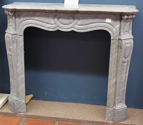 Louis XV style fireplace mantle: Louis XV style fireplace mantle, executed in carerra marble, the serpentine top above a relief carved face centered with scroll carved pilasters and rising on a molded base, 41''h x 47''w x 14''d