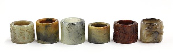 Group of Chinese Jade/Hardstone Thumb Rings: (lot of 6) Chinese jade and hardstone thumb rings, consisting of the following: one of deep red hues carved with bats alternating with shou emblems; one gray-green ring carved with characters; one whi