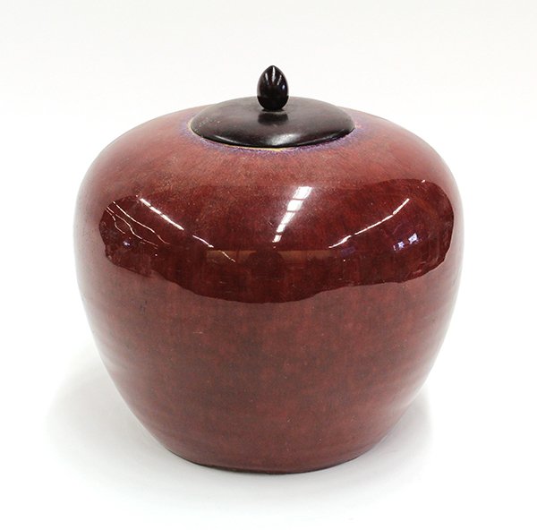Chinese Ox Blood Glazed Jar: Chinese oxblood glazed ceramic covered jar, 19th century, the tapering ground body coated with a mottled purple flambe encircling the mouth, with wood stand and lid (chips to foot), jar:7.5"h