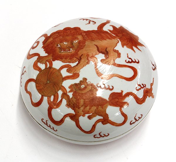 Chinese Enameled Circular Porcelain Container: Chinese gilt and iron-red enameled circular porcelain box, the domed lid featuring a fu-lion and cub playing with a ribbon tied brocade ball, the exterior of the box is decorated with bats above styli