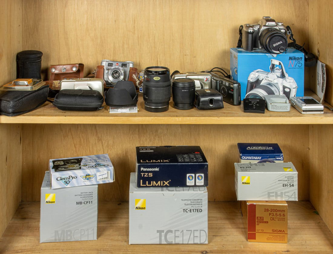 Two shelves including a group of digital cameras with lenses and various camera accessories (1 of 1)