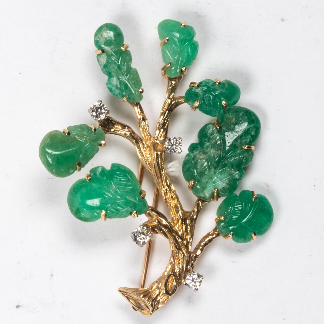 An emerald, diamond and 14k gold brooch: An emerald, diamond and 14k gold brooch of botanical design featuring 7 carved emerald beads, accented by round brilliant-cut diamonds; 12.10 grams; length: 2 in