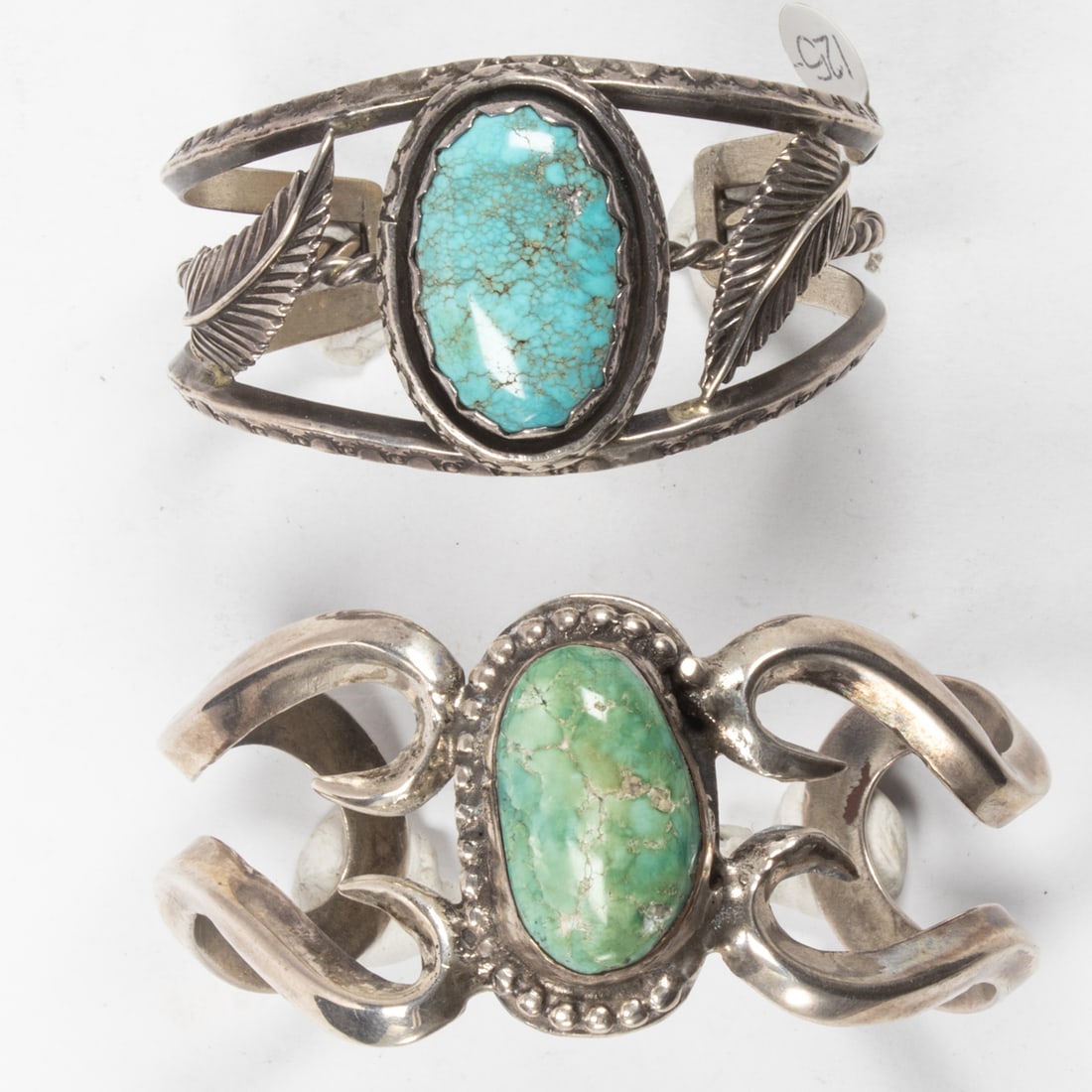 A pair of native american sterling and turquoise cuff bracelets: A pair of native american sterling and turquoise cuff braceletscomprising two buff bracelets, each with a oval turquoise cabochon; 99.1 gross grams