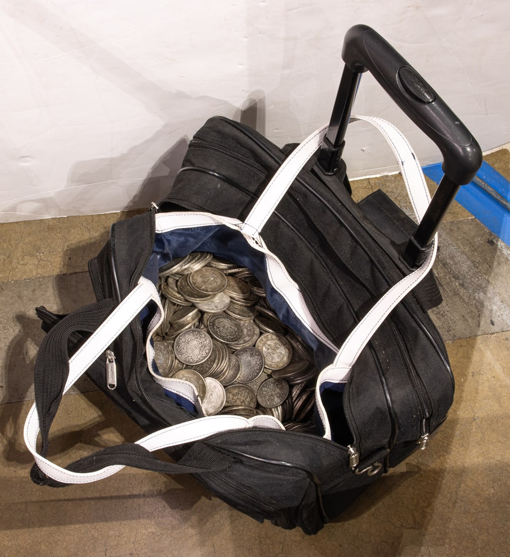 A rolling canvas suitcase full of hundreds of play or imitation metal coins: A rolling canvas suitcase full of hundreds of play or imitation metal coins
