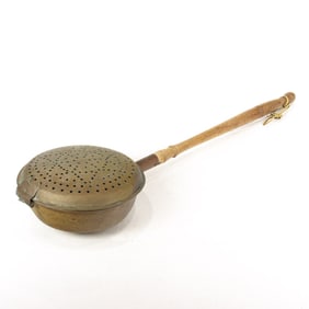 A vintage brass bedwarmer with a long turned wood handle