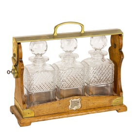 An English brass and oak tanatalus fitted with three cut glass decanters