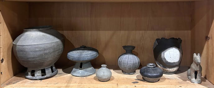 A shelf of Asian pottery items