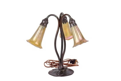 An Art Nouveau style patinated bronze table lamp with Zephyr gold favrile glass shades in the manner