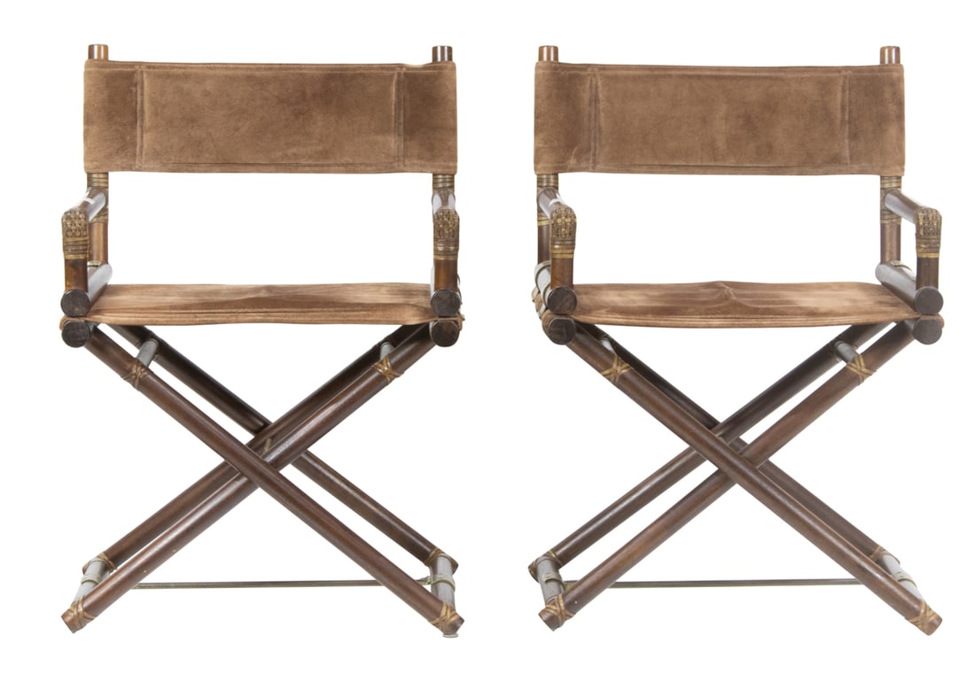 A pair of McGuire rattan safari chairs: A pair of McGuire rattan safari chairs, each folding chair with sueded upholstery and gold tone hardware, factory label to underside, 33.5"h x 22.75"w x 17"d