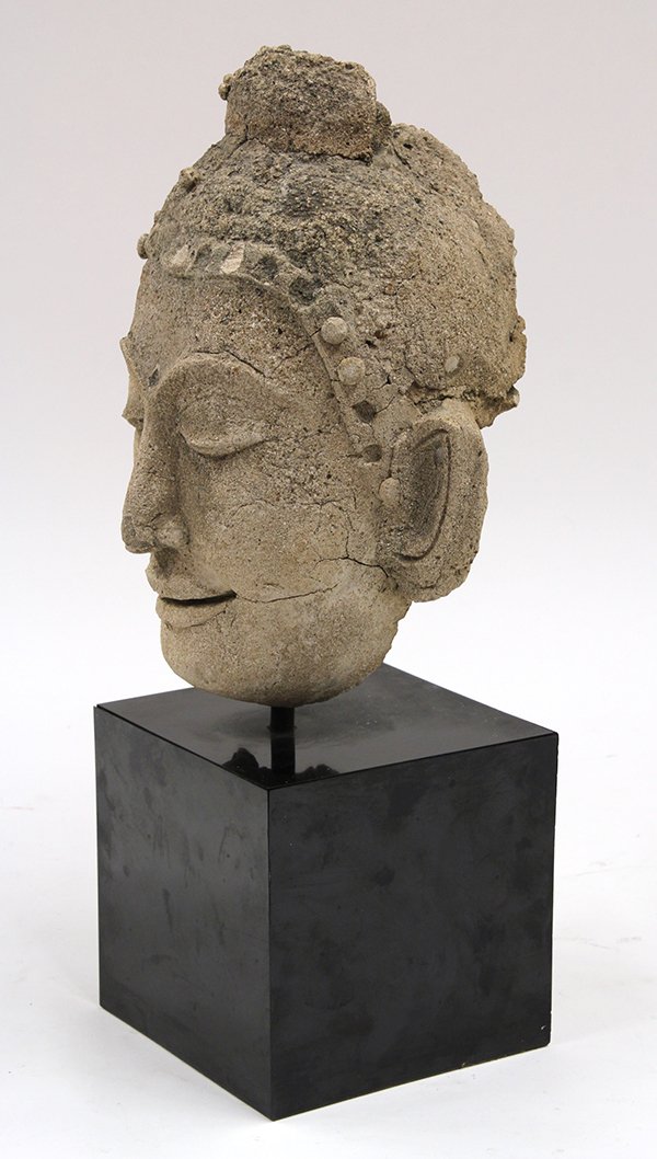 Southeast Asian Stucco Head of the Buddha: Southeast Asian grey stucco head of the Buddha, with a long oval face centered with a slender nose flanked by arched eyebrows above downcast eyes, stucco: 9.75"h, overall: 15.125"h