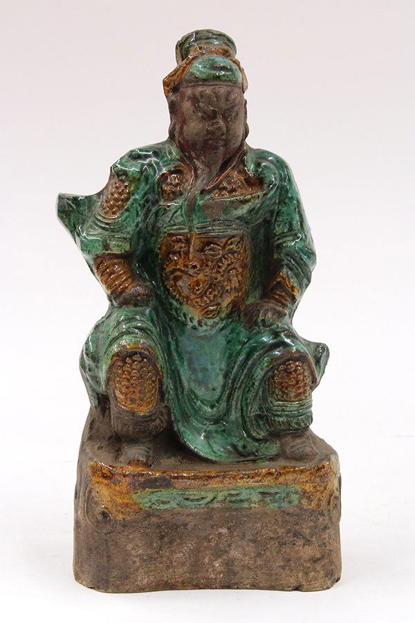 Chinese Glazed Ceramic Guardian Figure: Chinese glazed ceramic figure, Ming dynasty, of Guanyu in militaristic garb heightened in green and yellow glaze in contrast with the unglazed face, hands and shoes, set seated above a shaped plinth,