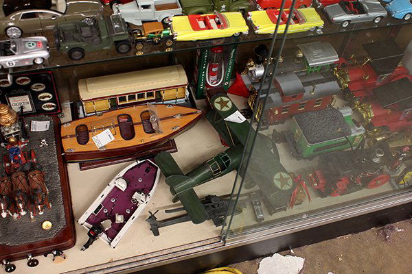 One shelf of miscellaneous travel collectibles: One shelf of miscellaneous travel collectibles including train cars, model cars, model sail boat, model airplane, etc.